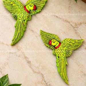 Wooden parrot wall hanging in green and red on a marble wall